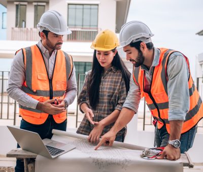 Civil engineer , Construction worker and Architects wearing hardhats and safety vests are working together at construction site ,building ,home in cooperation teamwork concept.